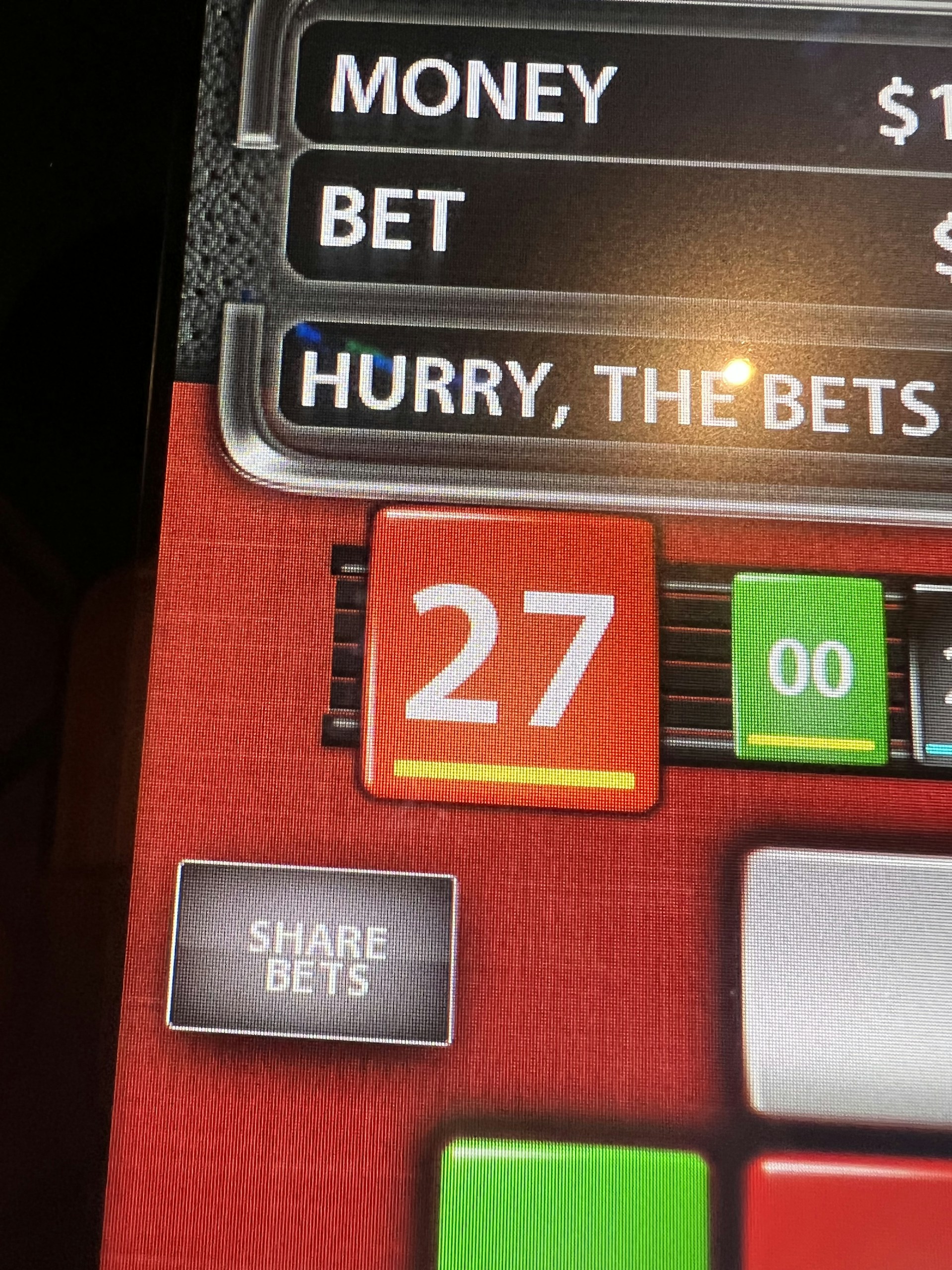 A digital display screen showing a casino betting interface, with text prompting to hurry bets and a highlighted number 27 in red. There are options for betting amounts and a 'share bets' button.
